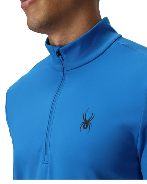 Man wearing a blue long-sleeve shirt with a brand logo on a white background