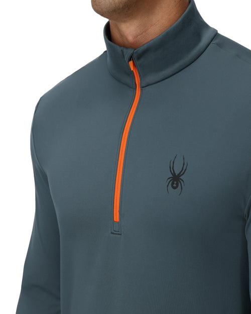 Man wearing a gray long-sleeve shirt with an orange zipper on a white background