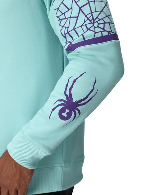 Man wearing a light blue sweater with geometric patterns and a brand logo on a white background