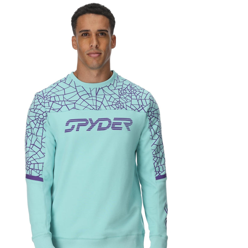 Man wearing a light blue sweater with geometric patterns and a brand logo on a white background