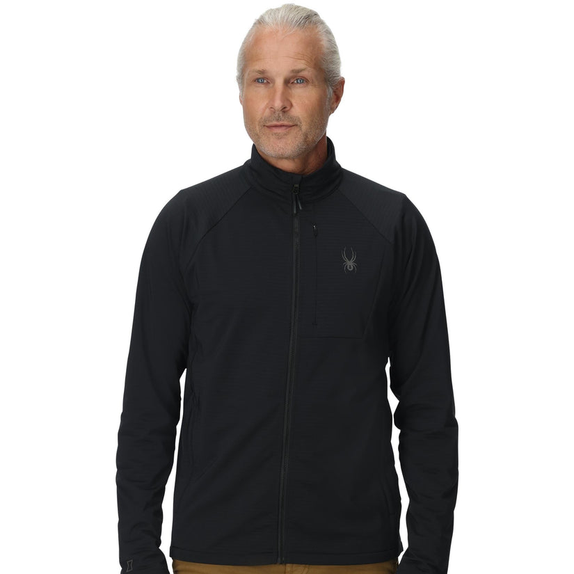 Man wearing a black jacket with a logo on a white background