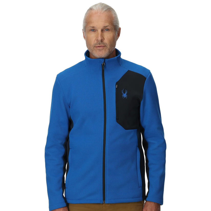 Man wearing a blue jacket with a black patch on a white background