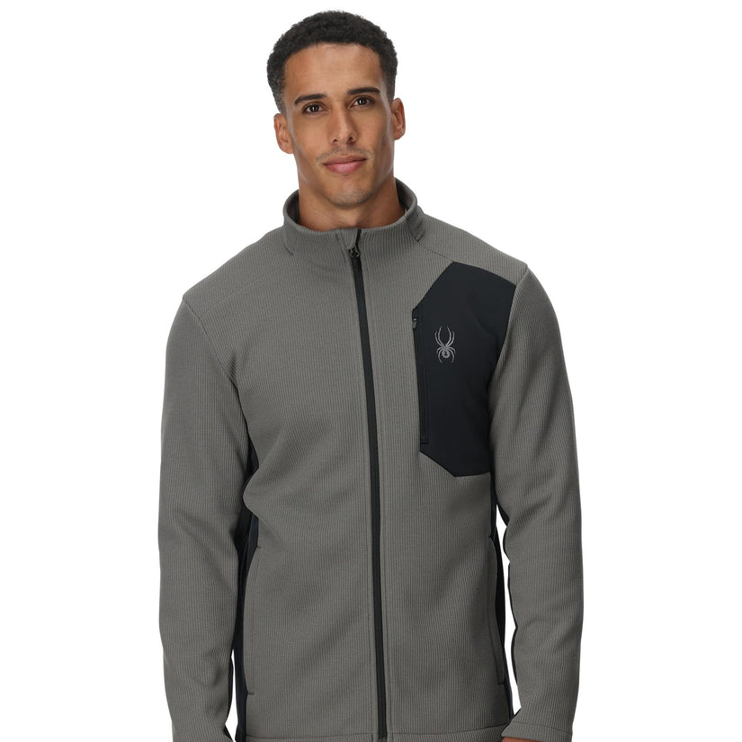 Man wearing a gray jacket with a black patch on a white background