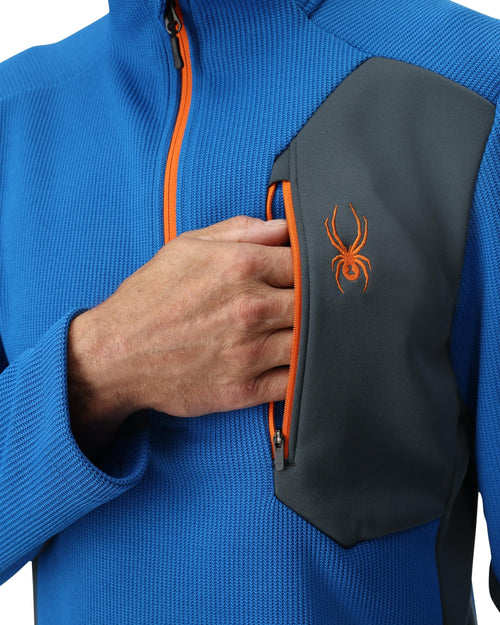 Man wearing a blue pullover with orange accents on a white background