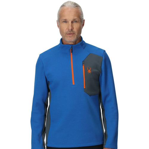 Man wearing a blue pullover with orange accents on a white background
