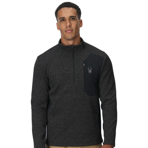 Man wearing a dark gray pullover with a logo on a white background