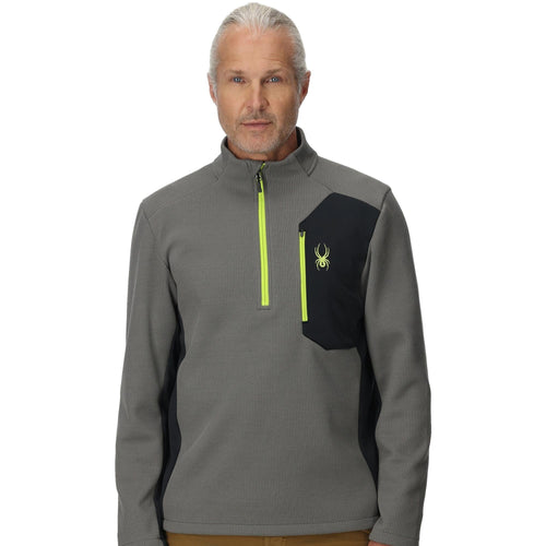 Man wearing a gray and black pullover with a logo on a white background
