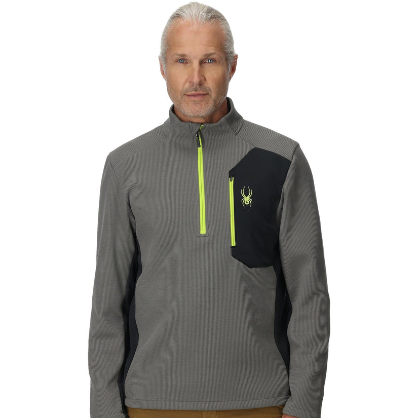 Man wearing a gray and black pullover with a logo on a white background