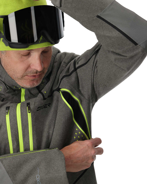 Person wearing a gray and green ski jacket with matching pants on a white background