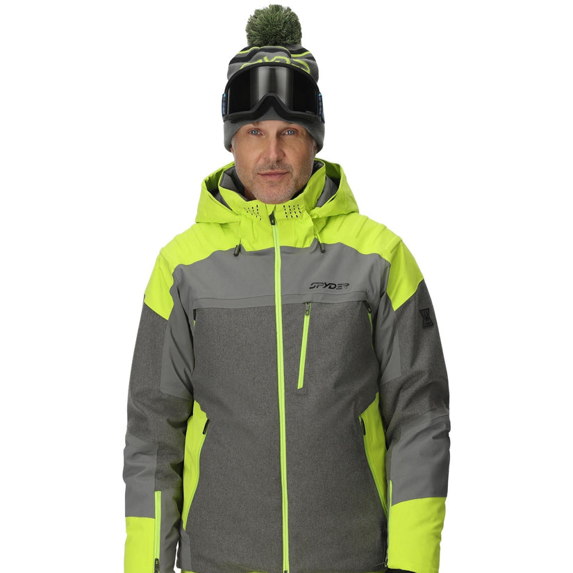 Person wearing a gray and neon green ski jacket with goggles on a white background