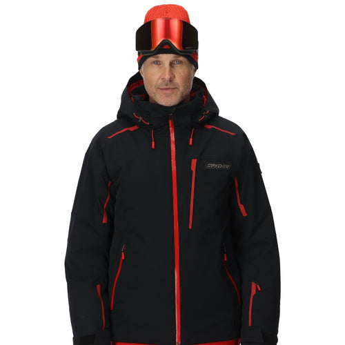 Man wearing a black and red ski jacket with goggles on a white background