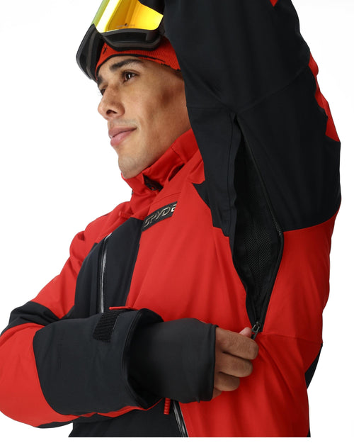 Person wearing a red and black ski jacket with goggles on a white background