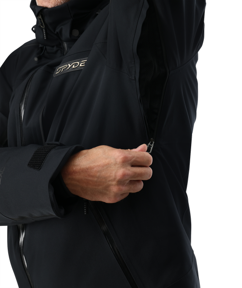 Man wearing a black ski jacket and blue pants on a white background