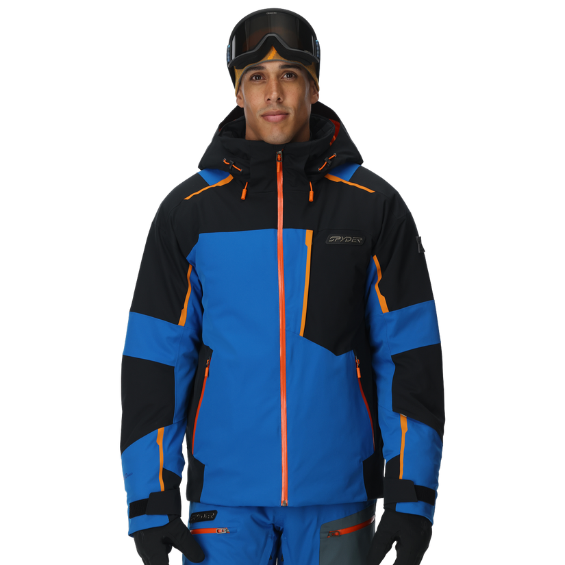 Person wearing a blue and black ski jacket with orange accents on a white background
