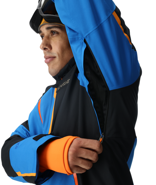 Person wearing a blue and black ski jacket with orange accents on a white background