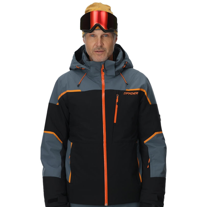 Person wearing a black and gray ski jacket with orange accents on a white background