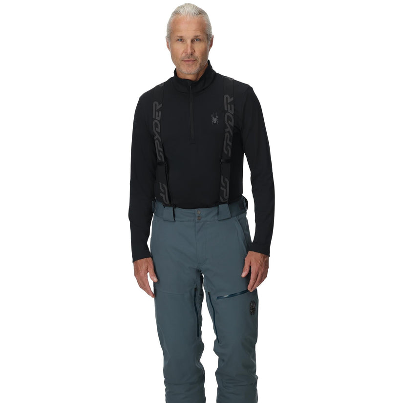 Man wearing a black long-sleeve top and gray pants on a white background