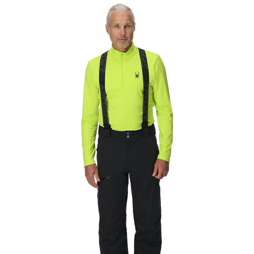 Man wearing a bright green jacket, black pants, and suspenders on a white background