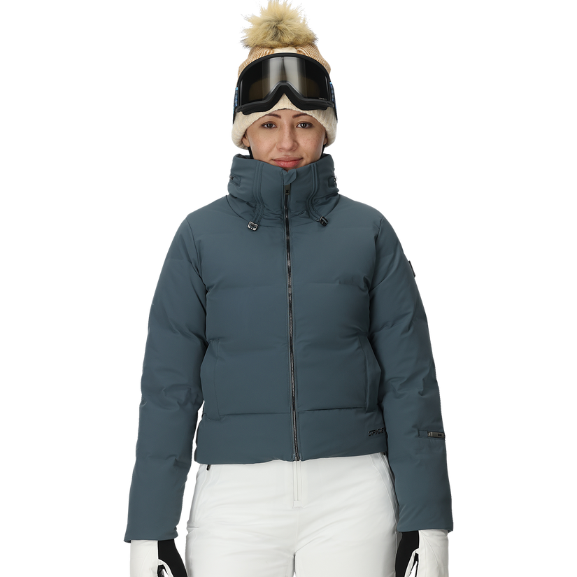 Person wearing a blue puffer jacket, white pants, and winter accessories on a white background