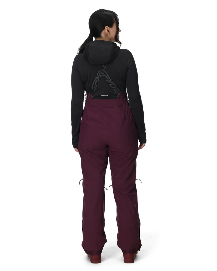 Person wearing a black jacket and maroon pants on a white background