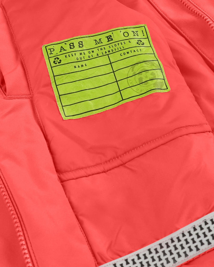 Close-up of a red jacket with a green label reading 'Pass Me On!' on a white background.